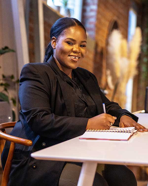 Zandile Chiwanza smiles as she writes in a notepad